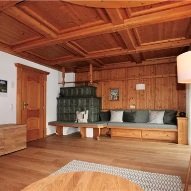 A cozy living room with wood paneling and a large window. The furnishings consist of a sofa, a table, and a television.