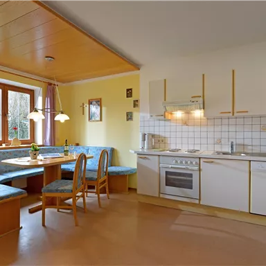 Eine moderne Küche mit einer gemütlichen Sitzecke. Sie ist hell und einladend, mit modernen Geräten und viel Licht.