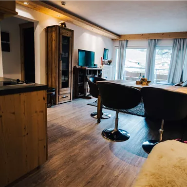 A modern living room with elegant furniture and large windows that let in plenty of daylight. The space has a cozy, inviting character.