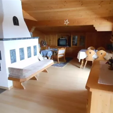 Ein gemütlicher Wohnraum mit Holzverkleidung und einer warmen Atmosphäre. Der Raum verfügt über einen Kamin, einen Esstisch und bequeme Sitzgelegenheiten.