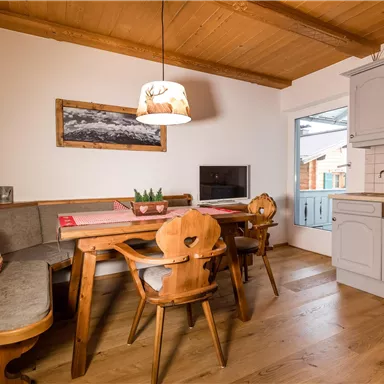 Eine gemütliche Küche mit einem Holztisch und bayerischem Stil. Der Raum ist hell und einladend mit einer schönen Aussicht nach draußen.