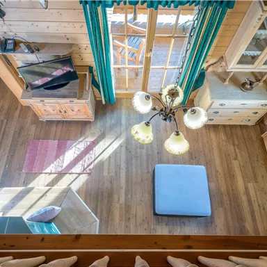 Eine gemütliche Holzstube mit großen Fenstern und viel natürlichem Licht. Ein ruhiger Raum mit einem modernen Möbelstil und klaren Linien.