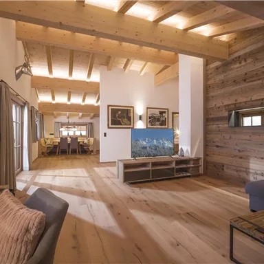 A modern living room with a wooden ceiling and a large television. The decor is cozy and inviting.