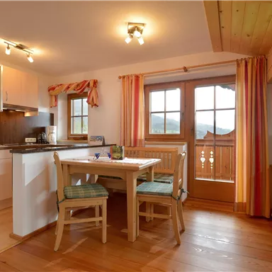 Eine gemütliche Ferienwohnung mit einer offenen Küche und einem Essbereich. Große Fenster sorgen für viel Tageslicht und einen Blick nach draußen.