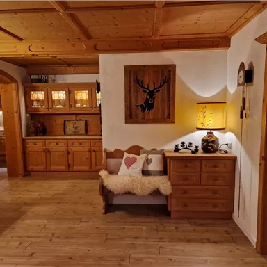 Ein gemütlicher Raum mit Holzregalen und einer Bank. An der Wand hängt ein dekoratives Bild eines Hirsches.