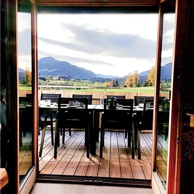 Ein gemütliches Restaurant mit einer Aussicht auf die Berge. Die Terrassentische sind bereit für Gäste.