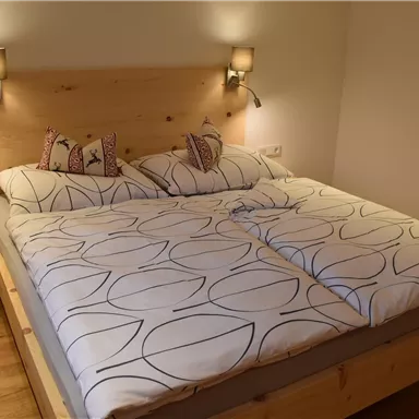 Ein gemütliches Schlafzimmer mit einem großen Doppelbett und holzverkleideten Wänden. Die Bettwäsche ist modern und ansprechend gestaltet.