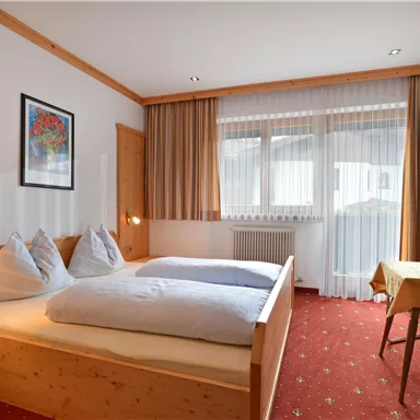 Ein gemütliches Schlafzimmer mit zwei Einzelbetten. Der Raum ist hell und freundlich mit einem Tisch und Stühlen.