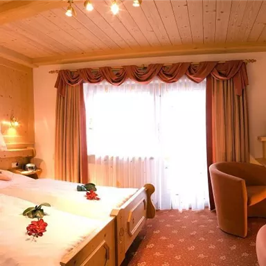 A cozy hotel room with two single beds and a workspace. Large windows provide plenty of daylight and create a pleasant atmosphere.