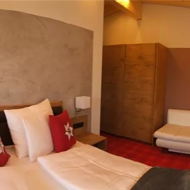 A modern room with two beds and a cozy sofa. Large windows provide plenty of daylight.