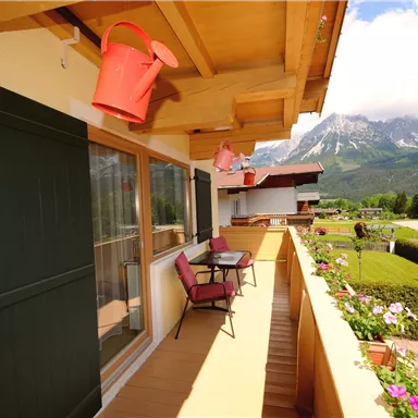 Ein schöner Balkon mit Blick auf die Berge. Es gibt zwei Stühle und Blumen auf der Brüstung.