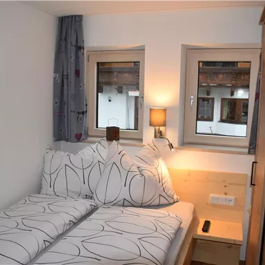 Ein gemütliches Schlafzimmer mit zwei Einzelbetten und modernen Kissen. Die Fenster lassen viel Licht hinein und strahlen eine einladende Atmosphäre aus.