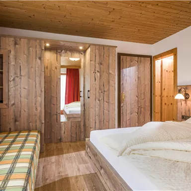 Ein gemütliches Schlafzimmer mit Holzverkleidung und einem Doppelbett. Der Raum verfügt über eine Sitzecke und sanfte Beleuchtung.