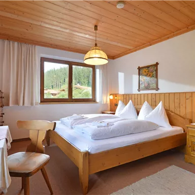 Ein gemütliches Schlafzimmer mit Holzverkleidung und zwei Betten. Das Zimmer hat ein Fenster mit Blick auf die Natur und eine einladende Atmosphäre.