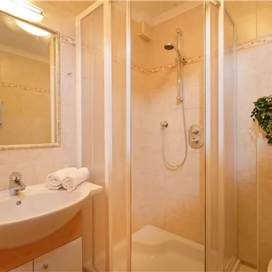 Ein modernes Badezimmer mit einer Duschkabine und einem Waschbecken. Sanfte Farbtöne und eine saubere, einladende Atmosphäre.