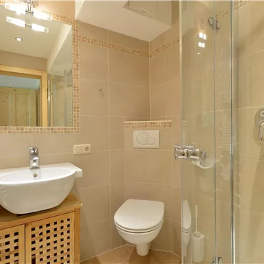 Ein modernes Badezimmer mit Dusche und Waschbecken. Helle Fliesen sorgen für eine frische und einladende Atmosphäre.