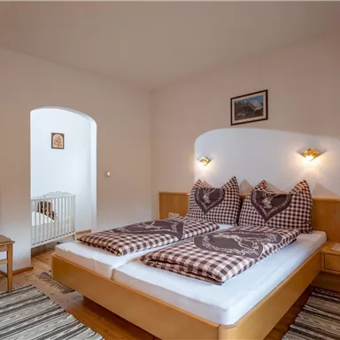 Ein gemütliches Schlafzimmer mit zwei getrennten Betten und karierten Bettbezügen. Im Raum befinden sich ein Stuhl und ein Teppich, der eine einladende Atmosphäre schafft.