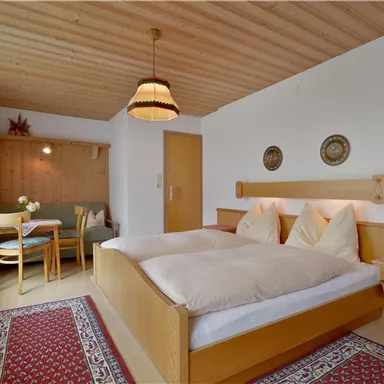 Ein gemütliches Schlafzimmer mit zwei Betten und Holzwänden. Im Hintergrund befindet sich ein Essbereich mit einem Tisch und Stühlen.