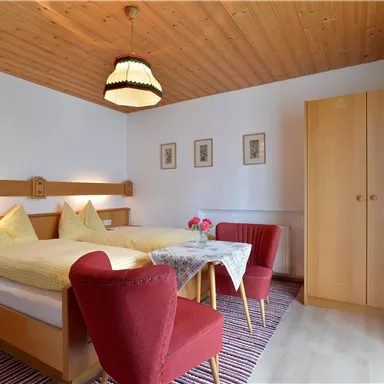 Ein gemütliches Zimmer mit zwei Einzelbetten und einem Tisch. Die Wände sind hell und die Einrichtung ist schlicht und funktional.