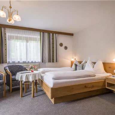 A comfortable room with two beds and a cozy seating area. Large windows provide plenty of daylight.