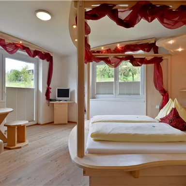 A bright room with modern furniture and large windows.  
The decor is cozy, with a table and colorful decorations.