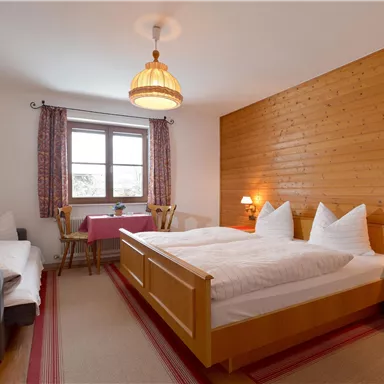 Ein gemütliches Schlafzimmer mit Holzvertäfelung und zwei Betten. Die Einrichtung ist modern und einladend, mit einem Tisch und einem Fernseher.