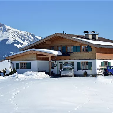 Ein schönes Haus in den Alpen, umgeben von Schnee. Im Hintergrund sind majestätische Berge zu sehen.