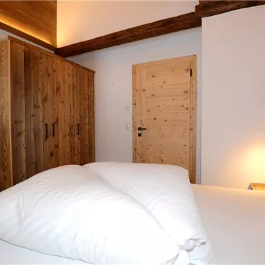 Ein gemütliches Schlafzimmer mit einem großen Bett und Holzschränken. Die warmen Farben schaffen eine entspannte Atmosphäre.