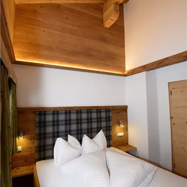 Ein gemütliches Schlafzimmer mit einem Holzbett und modernen Beleuchtungselementen. Die Einrichtung strahlt einen warmen und einladenden Charakter aus.