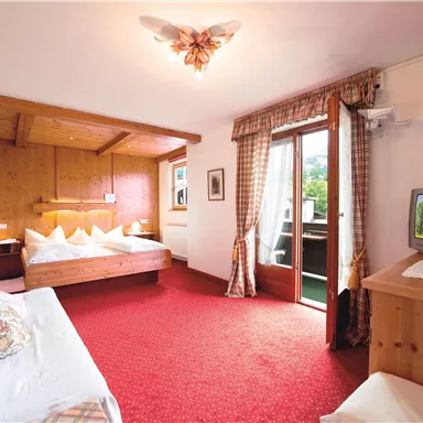 Ein gemütliches Hotelzimmer mit Holzverkleidung und einem großen Fenster. Das Zimmer ist hell und einladend, mit einem Doppelbett und einem Fernseher.