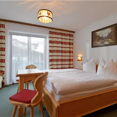 Ein gemütliches Zimmer mit Holzmöbeln und bequemen Betten. Der Raum verfügt über ein Fenster mit Aussicht und eine entspannte Atmosphäre.