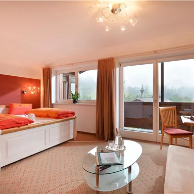 Ein stilvolles Schlafzimmer mit einem großen Bett und gemütlicher Einrichtung. Große Fenster sorgen für viel Tageslicht und einen schönen Ausblick.