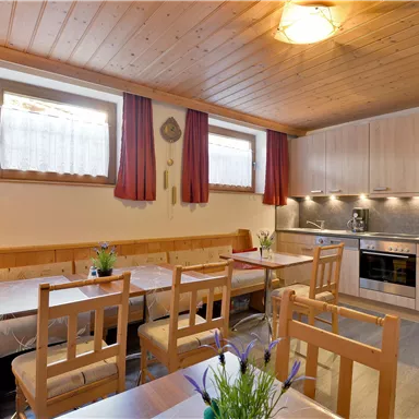 Eine gemütliche Küche mit Holzdecken und hellen Möbeln. Es gibt einen Esstisch mit Stühlen und eine moderne Küchenausstattung.