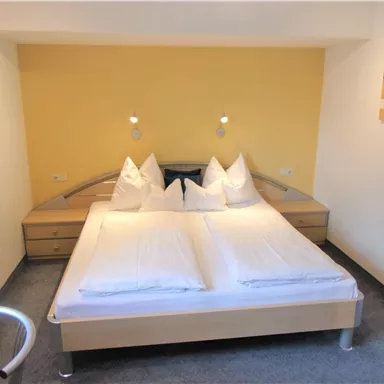 Ein modernes Schlafzimmer mit einem Doppelbett und hellen Wänden. Die Atmosphäre ist freundlich und gemütlich, ideal zum Entspannen.