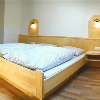 Ein gemütliches Schlafzimmer mit einem großen Holzbett und hellen Wänden. Neben dem Bett befinden sich zwei Nachttische mit Lampen.