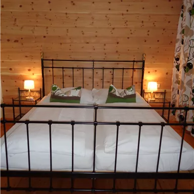 A cozy bedroom with a large bed and wood paneling. Two nightstands with lamps complement the warm atmosphere.