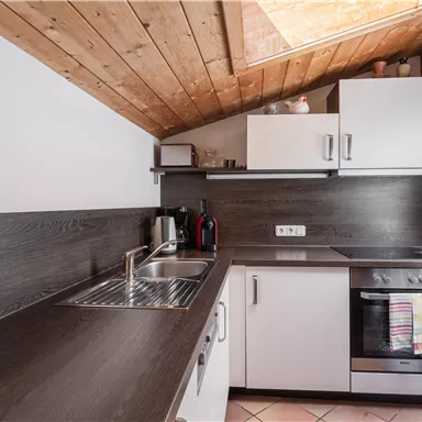 Eine moderne Küche mit Holzdecke und stilvollen Möbeln. Sie verfügt über eine Spüle, einen Herd und genügend Stauraum.