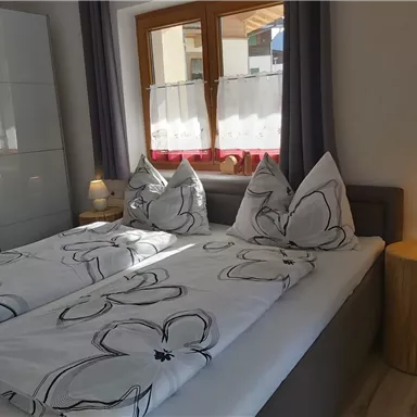 Ein einladendes Schlafzimmer mit zwei Einzelbetten. Die Fenster lassen helles Licht herein und die Einrichtung ist modern und gemütlich.