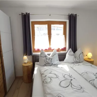 Ein gemütliches Schlafzimmer mit zwei Einzelbetten und modernen Möbeln. Die Fenster sind mit Vorhängen geschmückt und es gibt sanfte Beleuchtung.