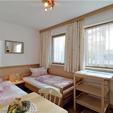 Ein gemütliches Zimmer mit zwei Einzelbetten und großen Fenstern. Die hellen Farben schaffen eine einladende Atmosphäre.