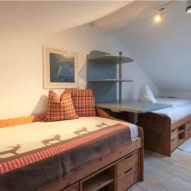 Ein gemütliches Schlafzimmer mit zwei Betten und einem Fenster. Die Wände sind hell und die Einrichtung ist aus Holz.