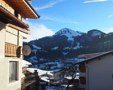 Ein malerisches Bergdorf mit schneebedeckten Bergen im Hintergrund. Der klare Himmel und die Holzverkleidung der Häuser verleihen der Szene Gemütlichkeit.