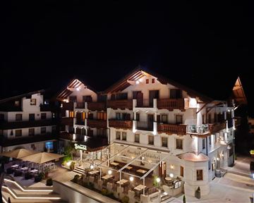 An elegant hotel building at night, illuminated by warm lights. Modern architecture with a cozy atmosphere and outdoor space.