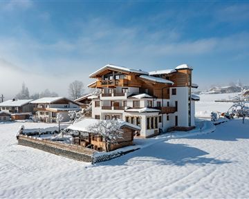 Ein wunderschönes, modernes Haus im Schnee. Die Umgebung ist malerisch und von schneebedeckten Bäumen umgeben.