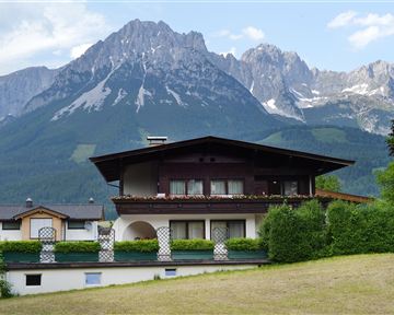 Ein schönes Haus vor einer beeindruckenden Berglandschaft. Die Umgebung ist grün und einladend.