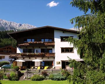 A charming house in alpine style, surrounded by mountains and trees. The sunny balconies invite you to relax.