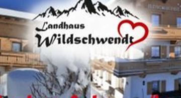 Ein gemütliches Landhaus im winterlichen Ambiente mit schneebedeckten Bergen im Hintergrund. Der Schriftzug "Urlaub auf dem Lande" betont die ländliche Idylle.