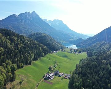 A picturesque landscape with green meadows, mountains, and a clear lake. The natural beauty of the surroundings radiates tranquility and peace.