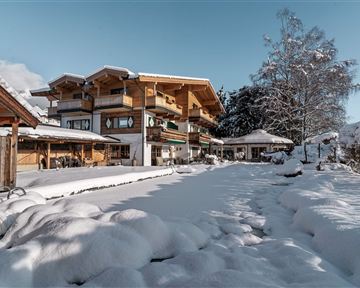 Ein schönes Gebäude im Winter mit Schnee bedecktem Garten. Der Himmel ist blau und die Landschaft wirkt friedlich.