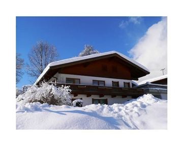 Ein gemütliches Haus im Schnee mit einem klaren blauen Himmel. Die Umgebung ist winterlich mit viel frischem Schnee.